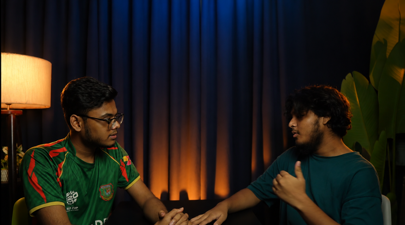 Two people talking in front of a blue curtain backdrop lit with orange light in the PlatiRoll studio